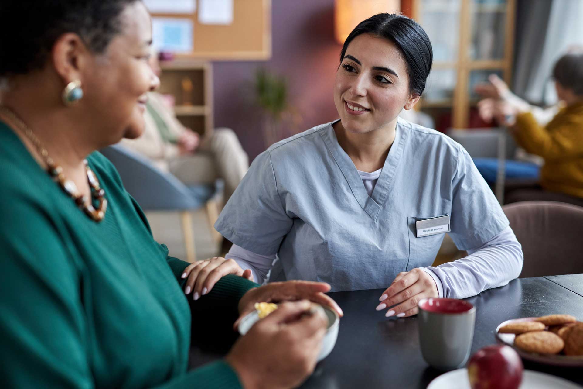 a nurse sitting with a women during breakfast